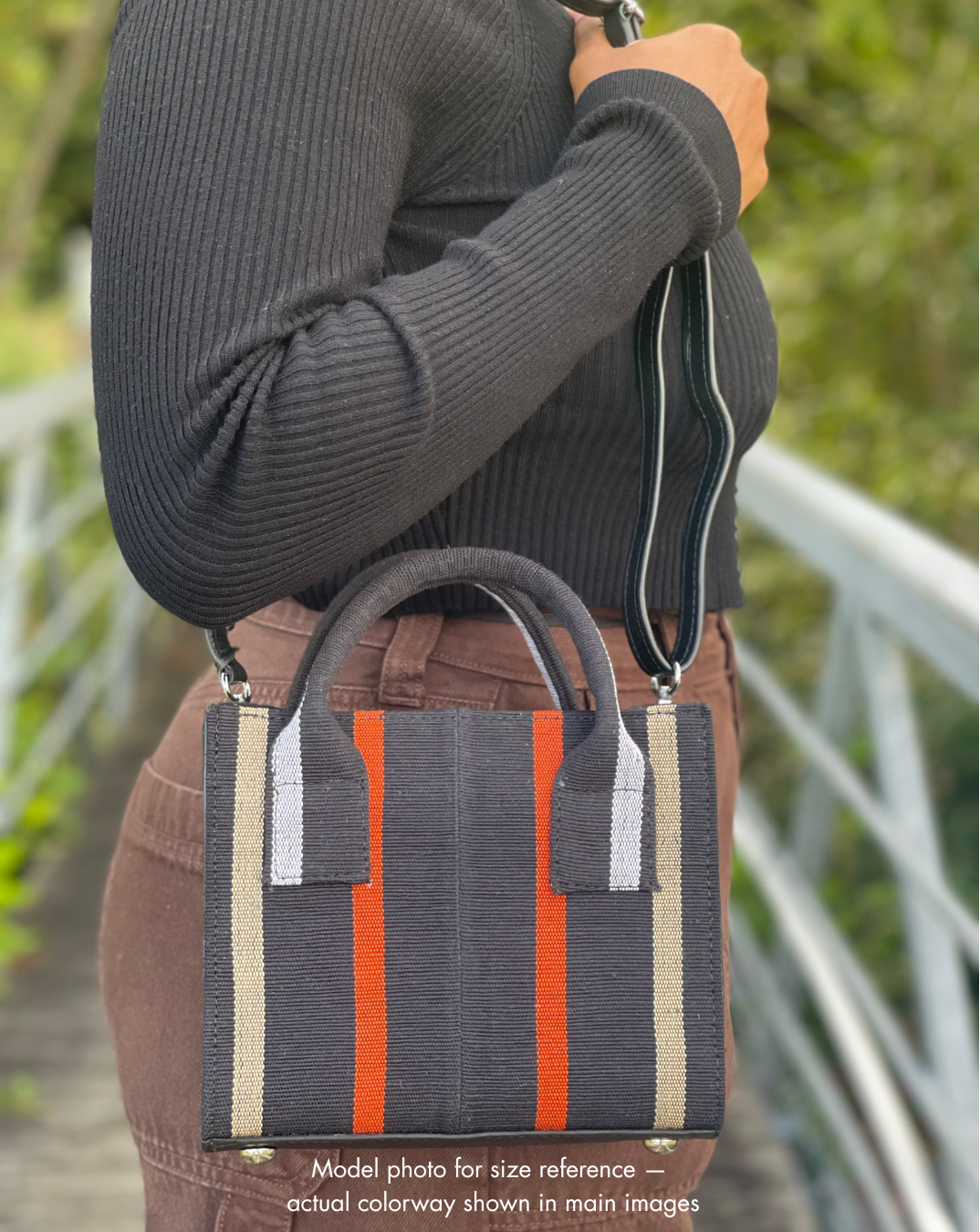 Person holding a striped handbag with a blurred background