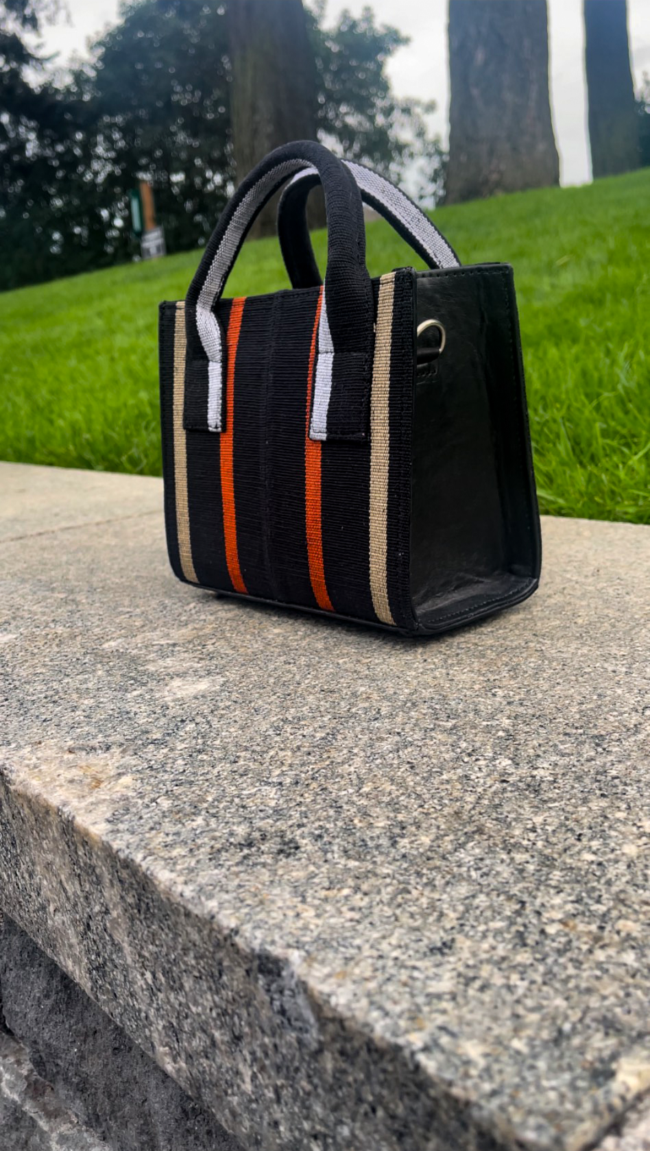 side view of aso oke mini tote bag in the black/gold/orange colorway